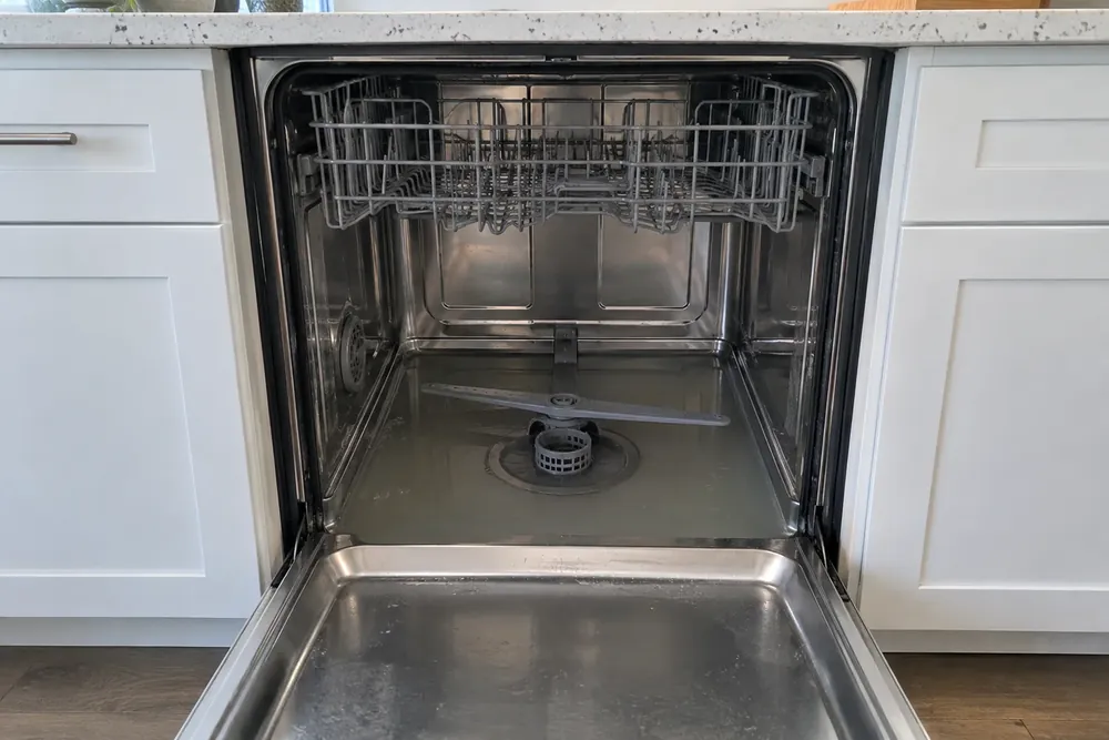 Cloudy water around the spray arm and round filter inside an open dishwasher