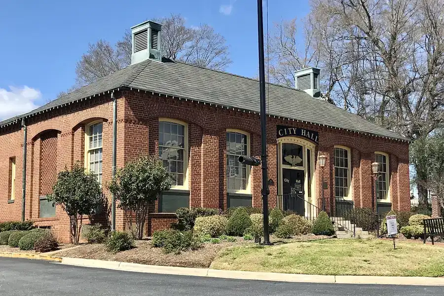 Former Belmont City Hall, a brick building with cupolas and shrubs, in Belmont, North Carolina