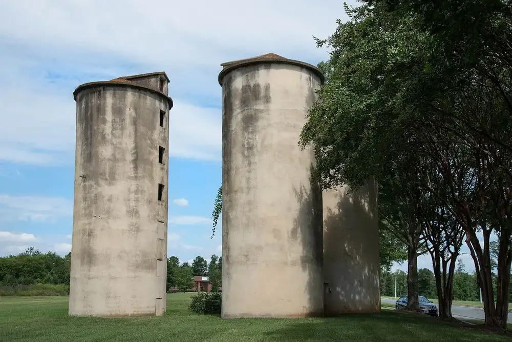 Historic concrete farm silos among trees and lawn in southeast Charlotte, North Carolina