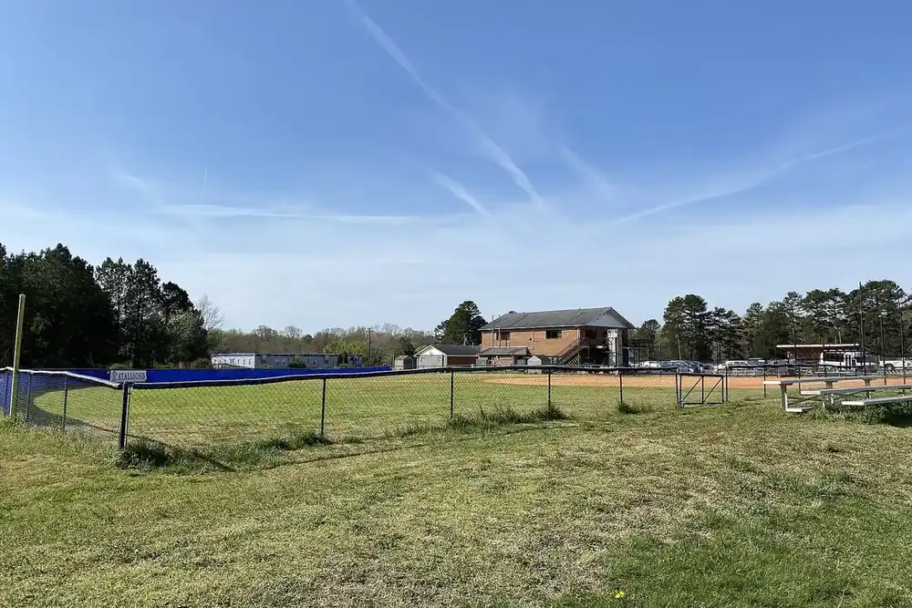 Fenced softball field and tree line under a blue sky in Mint Hill, North Carolina