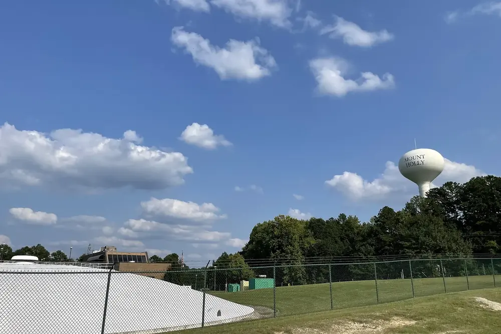 Water tower and fenced water plant grounds under a blue sky in Mount Holly, North Carolina