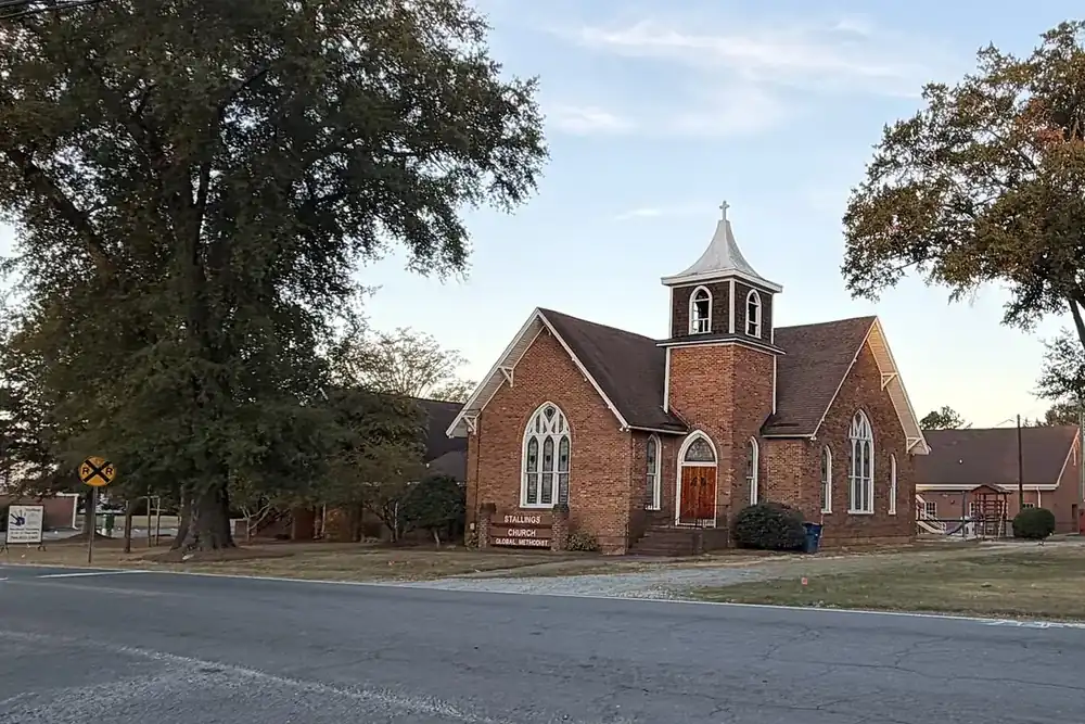Stallings Church, a brick chapel with a white bell tower, under tall oaks in Stallings, North Carolina