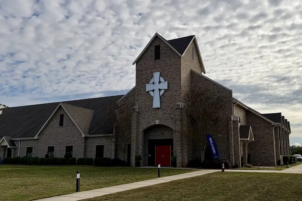 Front of All Saints Anglican Church with a large white cross and red doors in Weddington, North Carolina